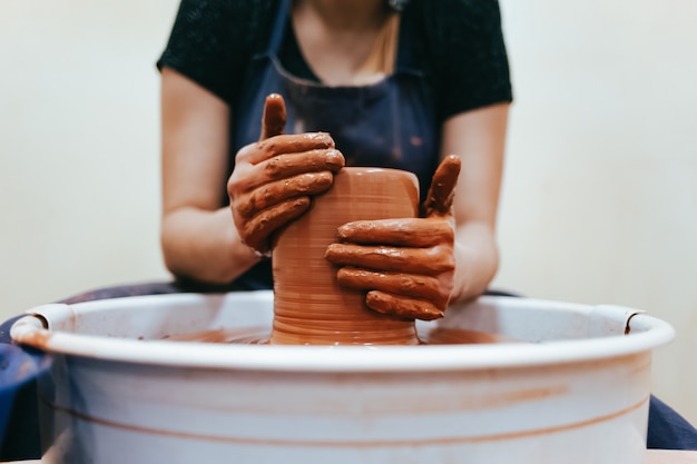 Potter behind the potter's wheel forms clay to create ceramic dishes