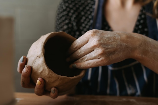 Potter woman's hands work with clay We make a clay bowl by molding Female hobby concept