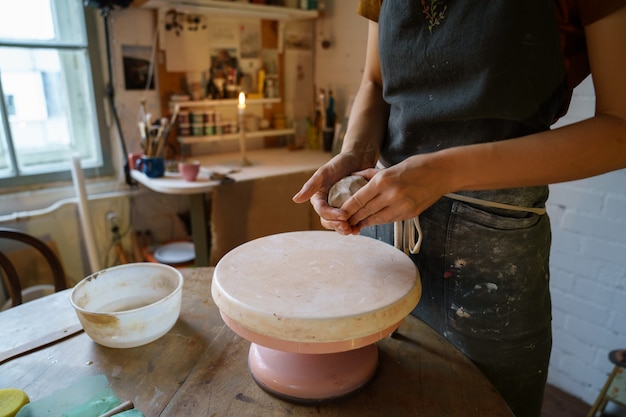 Pottery artist female molding clay on wheel ceramist in apron work with raw earthenware for potter