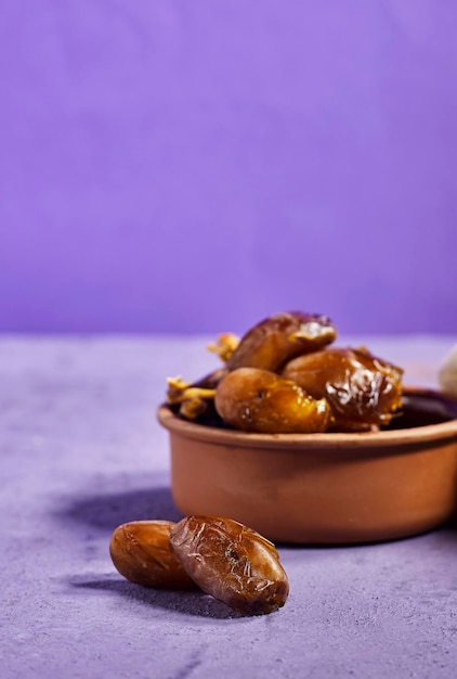 pottery bowl of pitted dates isolated on purple background