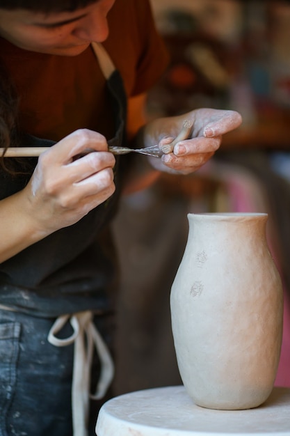 Pottery production artist use professional tools for molding raw clay and creating potter in studio