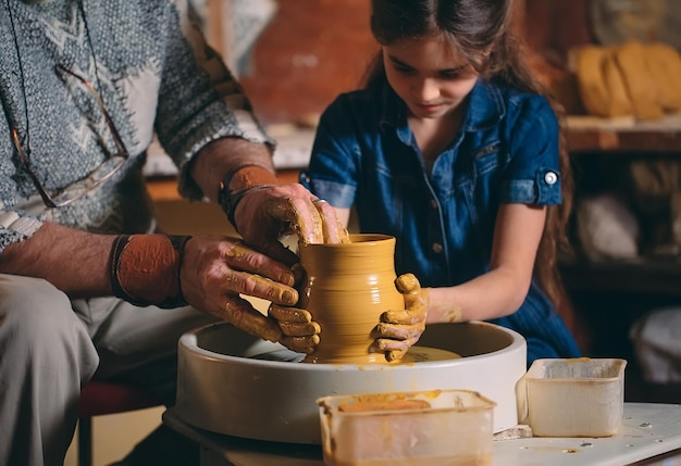 Pottery workshop. Grandpa teaches granddaughter pottery. Clay modeling.