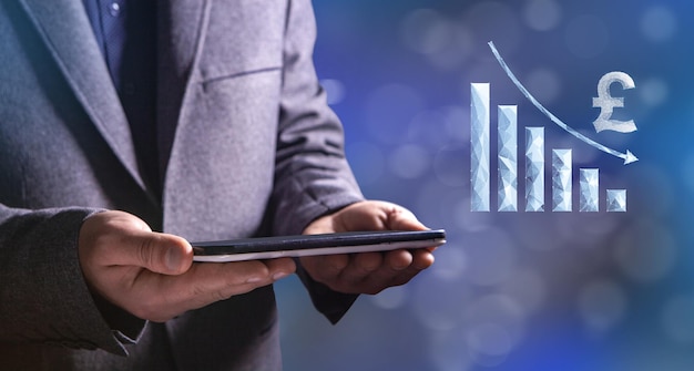 Pound from the network with the chart down The fall of the currency Man holding a tablet in his hand
