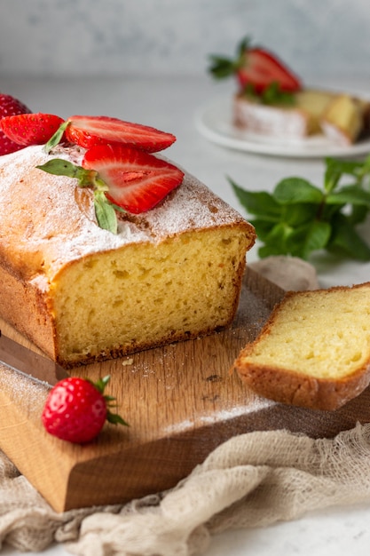 Pound or loaf cake with strawberry and mint on wooden board. 