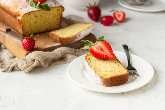 Pound or loaf cake with strawberry and mint on wooden board. 