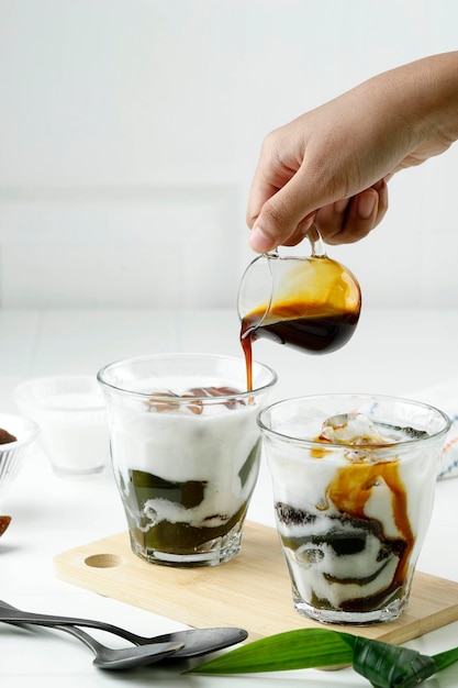 Pour Liquid Palm Sugar to the Glass with Green Grass Jelly Drink or Cingcau Hijau Cincau Ijo is Popular Street Food from Indonesia for Breaking the Fast