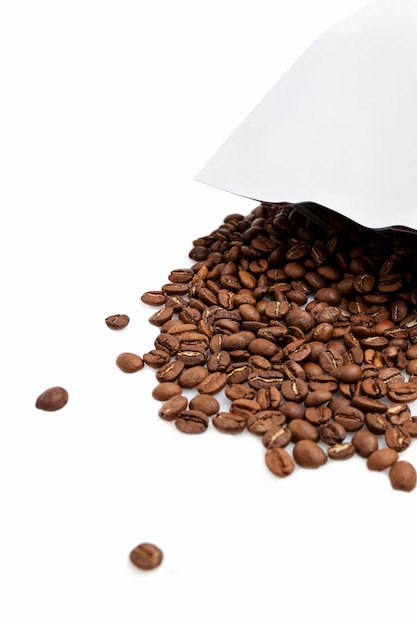 Poured roasted coffee beans from the package to prepare an aromatic drink Isolated on white background Vertical Closeup Space for text