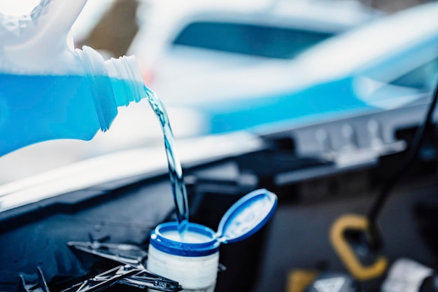 Pouring antifreeze Filling a windshield washer tank with an antifreeze in winter cold weather