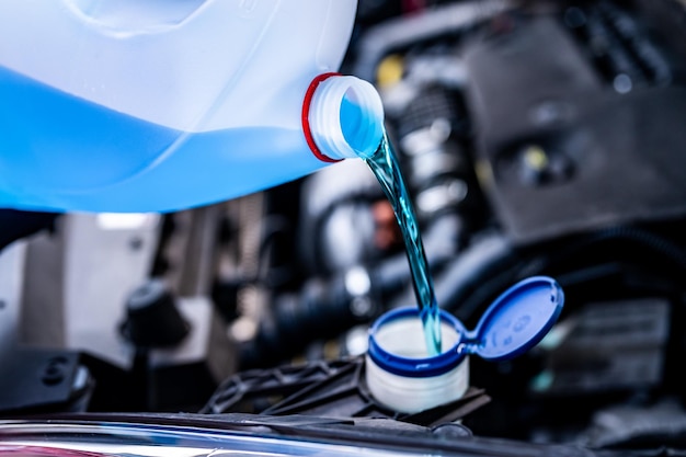 Pouring antifreeze Filling a windshield washer tank with an antifreeze in winter cold weatherxDxA