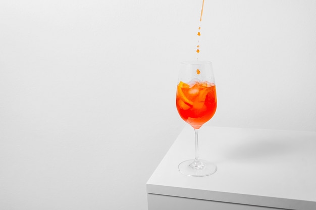 Pouring aperol in wine glass with ice on white background