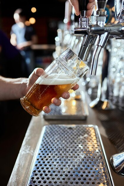 Photo pouring beer into a mug in a beer bar closeup beer bottling in the restaurant the bar counter