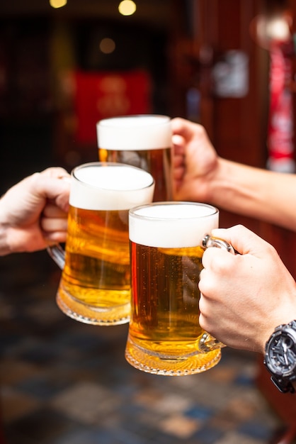 Pouring beer standing at the bar counter. Large craft wise beer in tap in cafe or pub menu. Toasting with friends at the bar