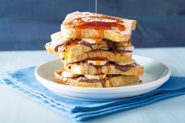 Pouring caramel over french toasts with banana chocolate sauce for breakfast