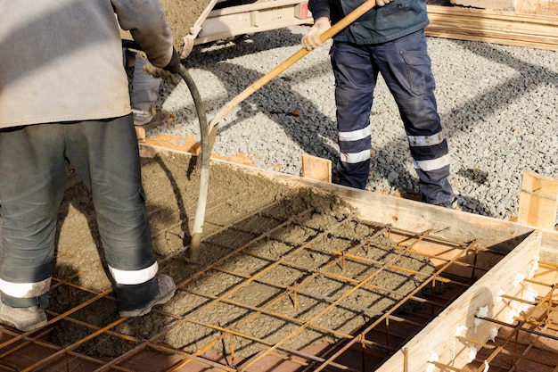 Pouring cement or concrete with a concrete mixer truck construction site with a reinforced grillage foundation Workers settle and level the concrete in the foundation