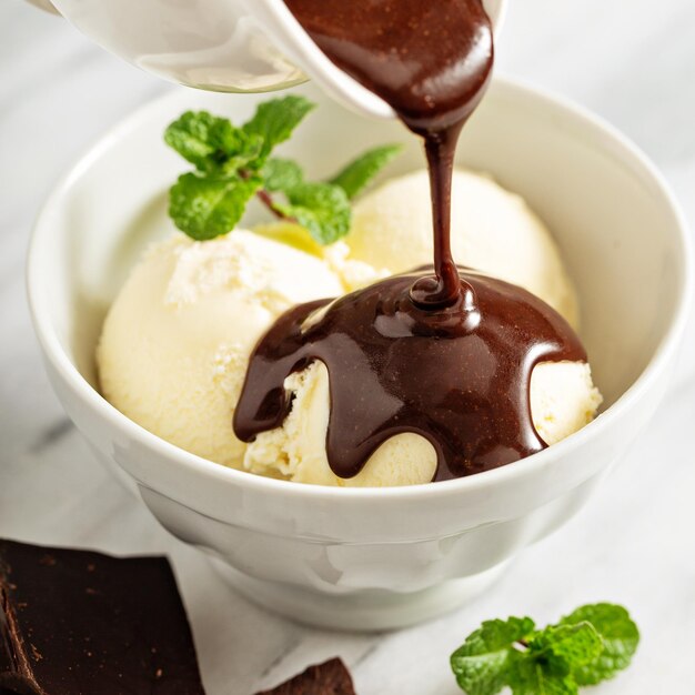 Photo pouring chocolate sauce on ice cream