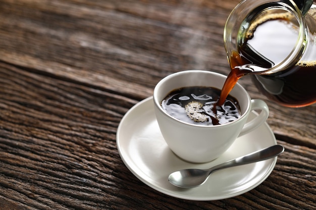 Pouring coffee with smoke on a cup on wooden background