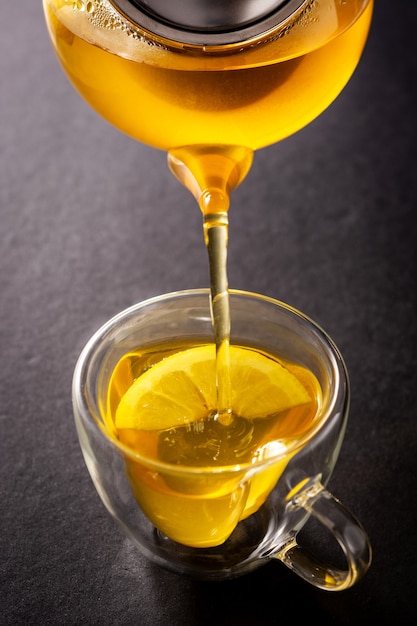 Pouring ginger tea with lemon and honey in a cup