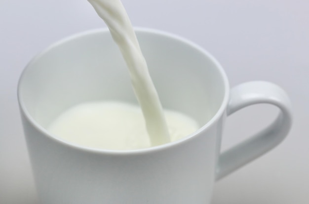 Pouring a glass of milk creating splash on a white background.