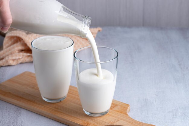 Pouring homemade kefir buttermilk or yogurt with probiotics Yogurt flowing from glass bottle