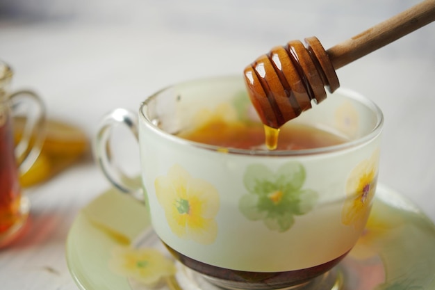 Pouring honey in green tea on table