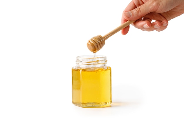 Pouring honey Woman hand holding wooden honey dipper drizzler with liquid honey isolated on a white