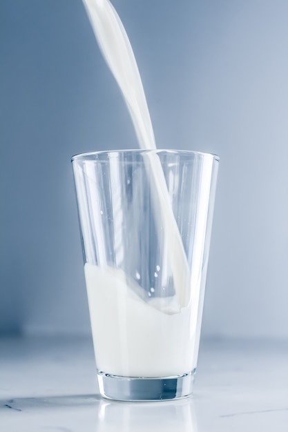 Pouring milk into glass on marble table