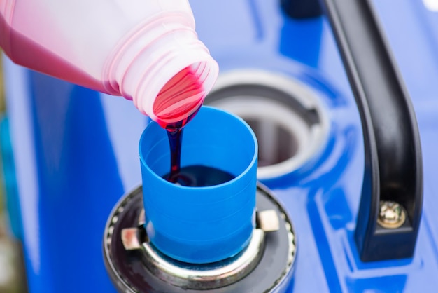 Pouring oil to measuring cup to add it to fuel tank