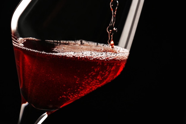 Pouring red wine on dark background