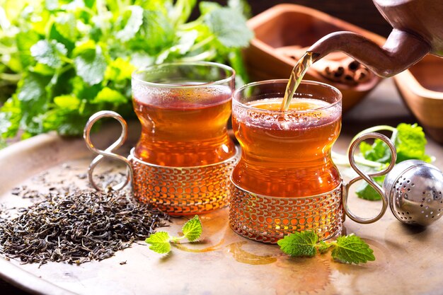 Pouring tea from teapot into glass