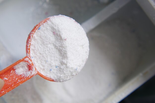 Pouring washing powder from a plastic spoon