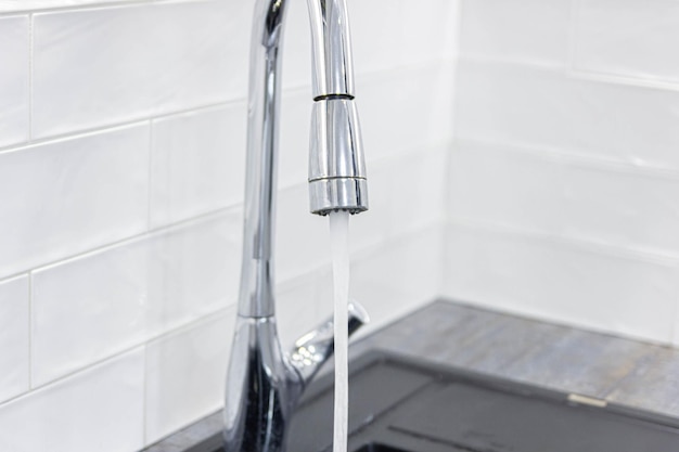 pouring water from the faucet in the kitchen the concept of energy saving water saving