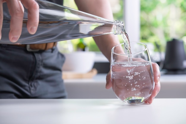 Pouring water into glass in the kitchen