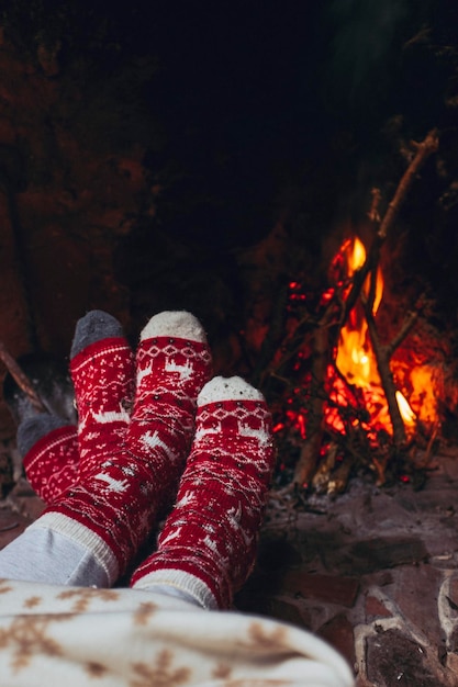 Pov of couple feet warming near fireplace at home or chalet room Holiday vacation in christmas time Romantic people enjoy relationship and tenderness looking fire indoor Xmas socks red and white