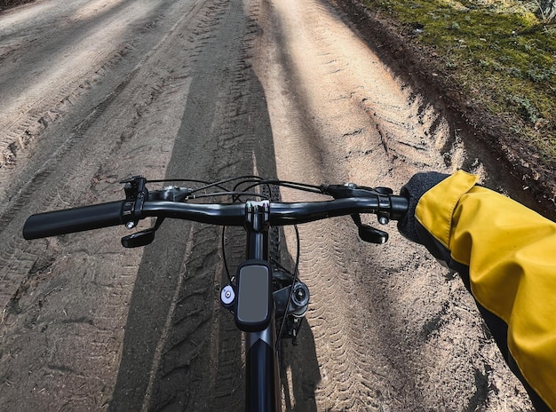 POV of riding a bike Closeup of bycycle handlebar with forest gravel road background