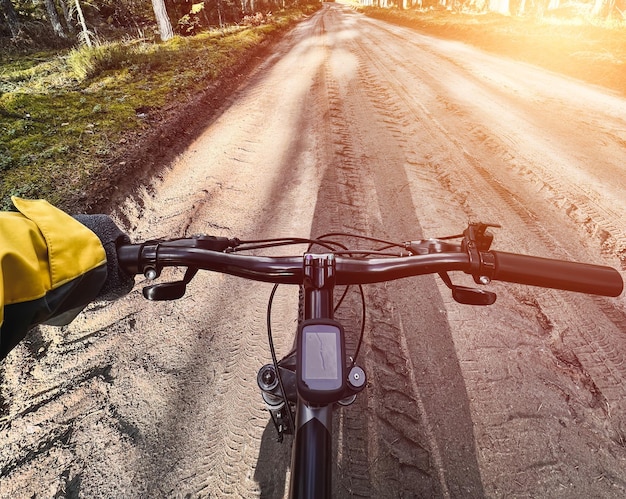 POV of riding a bike Closeup of bycycle handlebar with forest gravel road background