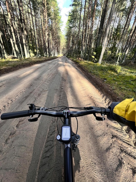 POV of riding a bike Closeup of bycycle handlebar with forest gravel road background