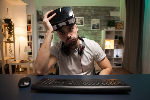 Photo pov of young man taking off his virtual reality goggles after losing at online games.