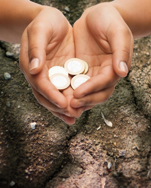 Photo poverty, starvation, ecology and charity concept - closeup of female hands holding euro coins over ground background