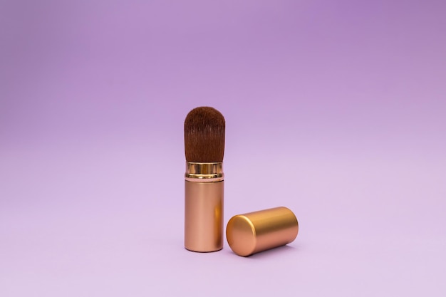 Powder brush in gold bottle with magenta background travel cosmetics