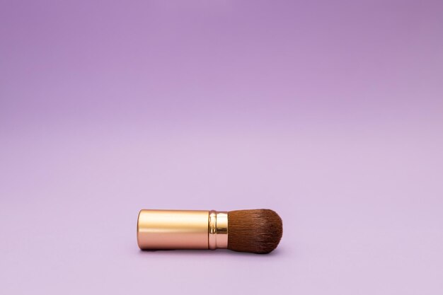 Powder brush in gold bottle with magenta background travel cosmetics