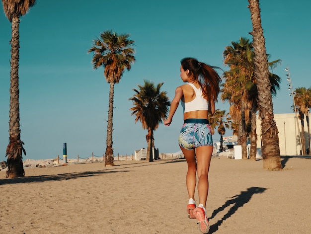 Power and balance. Rear view of beautiful young woman in sports clothing jogging while exercising outdoors