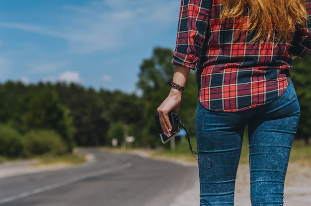 Power bank with a phone in the girl's hand. Against the background of the road.