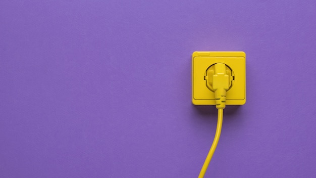 Photo a power cord plugged into an outlet on a purple background. space for text.