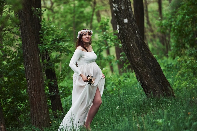 Power of nature. Beautiful pregnant woman in dress have a walk outdoors. Positive brunette