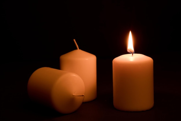 power outages concept, three candles, one with flame and two reserve, on the desk, dark background