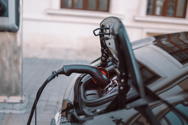 Power supply for hybrid electric car charging battery on urban europe street with blurred nature bac...