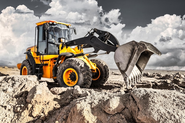 Powerful bulldozer or loader moves the earth at the construction site against the sky An earthmoving machine is leveling the site Construction heavy equipment for earthworks