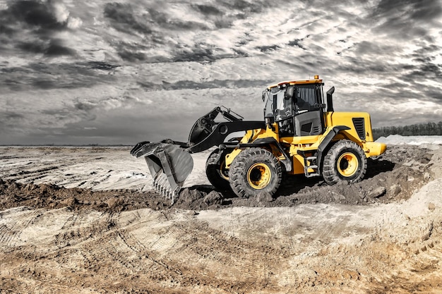 Powerful bulldozer or loader moves the earth at the construction site against the sky An earthmoving machine is leveling the site Construction heavy equipment for earthworks