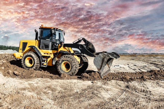 Powerful bulldozer or loader moves the earth at the construction site against the sky An earthmoving machine is leveling the site Construction heavy equipment for earthworks