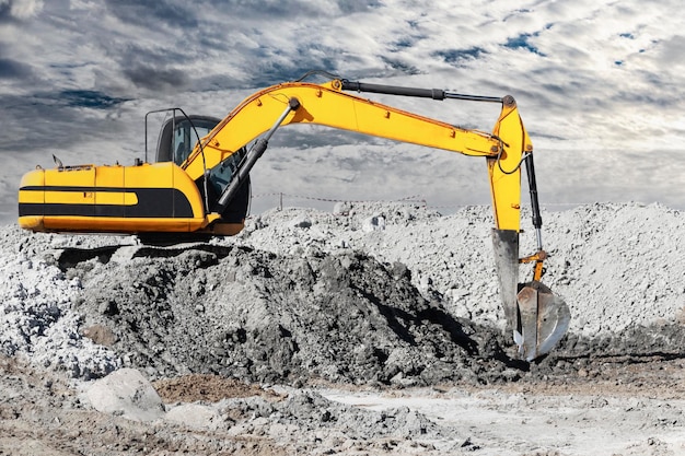 A powerful caterpillar excavator digs the ground against the evening sunset Earthworks with heavy equipment at the construction site Excavator in contrast against the sky